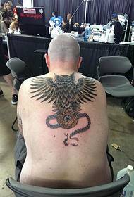 Man with beautiful pendant and owl tattoo pictures on the back
