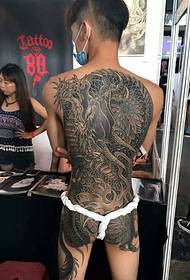 पीठ पर युवक का दुष्ट ड्रैगन टैटू अधिक आकर्षक है।