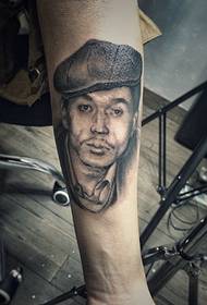 swart en wyt portret tattoo fan middelbere leeftyd op 'e earm