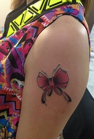 girl's arm small bow tattoo