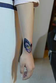 girl's arm full of colorful feather tattoo