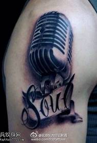 A realistic, domineering microphone tattoo on the shoulder