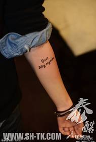 Perempuan mempersenjatai sebuah pola tato kata bahasa Inggris