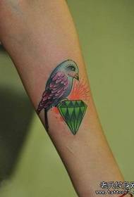Girls arm with a colored diamond bird tattoo