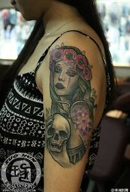 Работи тетоважа на череп девојка од рака, покажувајќи го тетоважата