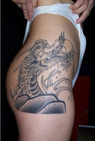 žena pokazuje uzorak zmaja tetovaža kuka