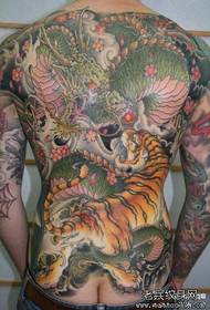 Spatele bărbatului este super cool și dominator plin de modelul de tatuaj de luptă pentru dragon și tigru