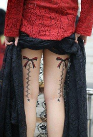 деликатна снимка на татуировка с лък и дантела на крака