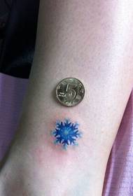 woman's leg small colorful snowflake tattoo