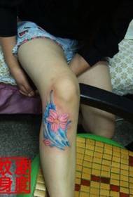足の膝の上の青いベニバナの入れ墨の写真
