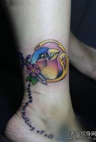 Tyttöreät jalat mukavilla värillisillä lintujen tatuointikuvioilla