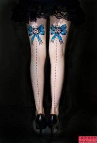 a beautiful bow tattoo on the thigh