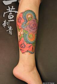 Vackra och vackra färgade orm- och rosa tatueringsmönster på benen
