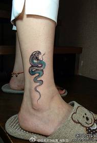 Malgranda serpenta tatuaje mastro sur la kruroj de knabinoj