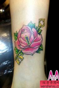 Bela virina roza seruro kaj ŝlosila tatuaje ŝablono sur la kruroj de knabinoj