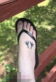 女の子の足の甲に黒と白の小葉のタトゥーの写真
