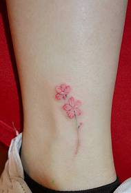 唯 бели боси крака върху красивата малка татуировка на цветя