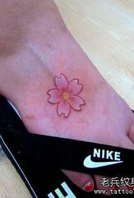 tjej vänder en liten tatuering mönster med körsbärsblommor