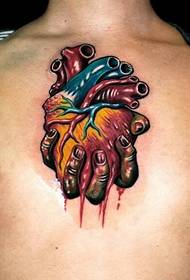 męska ręka w klatce piersiowej trzyma serce tatuaż