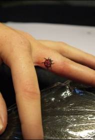 Un picculu mudellu di tatuaggi di ladybug pittatu à l'internu di u dito