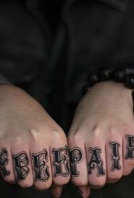 Hand with two fingers has a stylish English tattoo