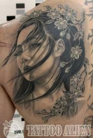 Tillbaka porträtt av den vackra asiatiska kvinnan med blommande tatueringsblommor