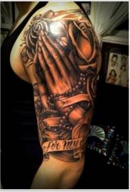 Didelės rankos juodai baltos meldžiančios rankos su raidžių ir gėlių tatuiruotės modeliu