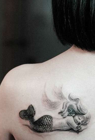 Musteella pieni merenneito-tatuointi olkapäällä