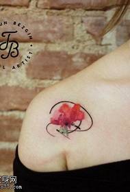 a small flower tattoo on the shoulder