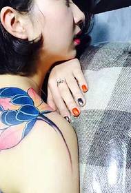 Seksīgs lotosa tetovējums uz modes dievietes pleca
