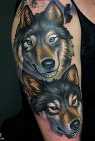 Two wolf dog tattoos on the shoulders
