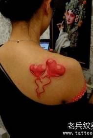 Female girl with a colorful love tattoo on the shoulder