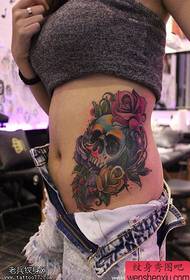 la figura del tatuaggio ha raccomandato un tatuaggio con teschio rosa sul fianco della donna
