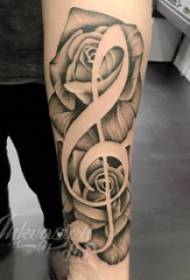Musikalisk tatuering, flickans arm, blomma och tatueringsbild