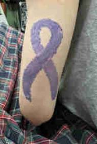 Krāsota tetovējuma meitenes roka uz krāsainas lentes tetovējuma attēla