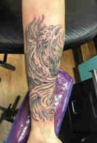 Materiál tetovania na ramene, tetovanie mužského fénixa na čiernej ruke
