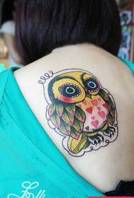 El tatuaje de búho de color de espalda de la mujer funciona por el espectáculo de tatuajes