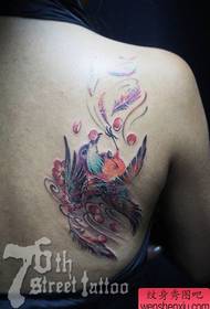 Bella ragazza con un tatuaggio colorato uccello sul retro della ragazza