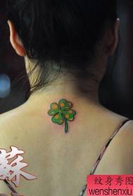 красочная татуировка из четырех листьев клевера на спине девушки