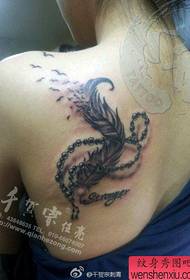 Kobiece ramiona popularny wzór tatuażu z piór i naszyjnik