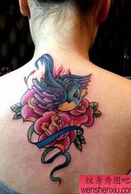 Lány szép látszó fecske és rózsa tetoválás a hátán