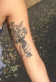 Le bras de la fille sur la photo de tatouage de la main de la pointe du gris et de la fleur noire