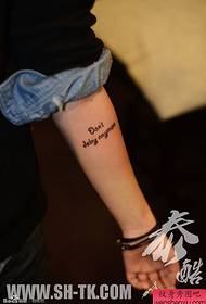 Femeia brațează un model de tatuaj în cuvântul englezesc