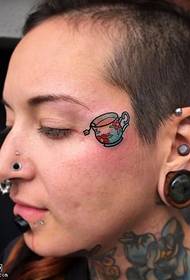 Small teacup tattoo on the face
