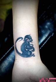 Śliczny atramentowy tatuaż na nadgarstku małpy