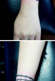 Zglobovi djevojaka, mali i lijepi uzorak tetovaže crne i bijele narukvice