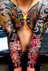Męski dominujący podwójnie w połowie duży tatuaż na ramieniu kwiatowym