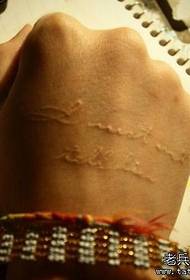 Девушка вручает белую букву татуировки