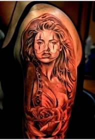 Na ramenu smeđa seksi djevojka s uzorkom tetovaže ruža