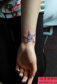 Mergaitės riešas su penkiakampėmis žvaigždutėmis ir žvaigždėtu tatuiruotės modeliu